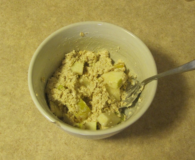 Oatmeal yogurt and fruit mixed together in a white bowl with a spoon