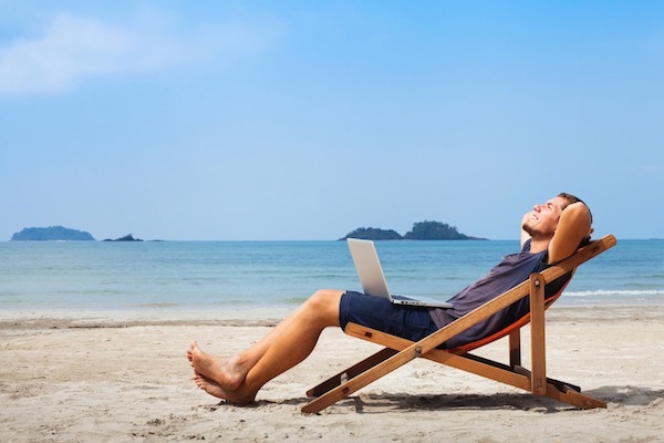Digital nomad working on the beach with his laptop