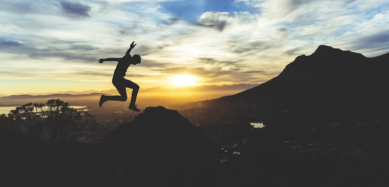 Man jumping over mountains to signify overcoming obstacles to success