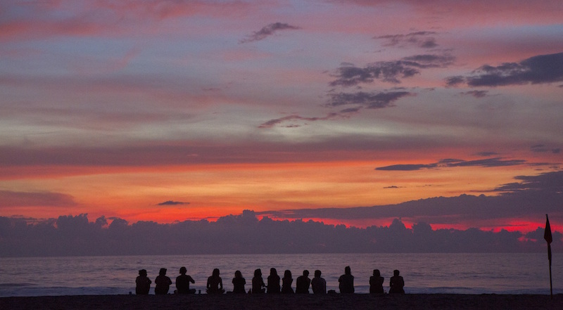 A group of friends sitting on the beach watching the sunset to signify finding your tribe