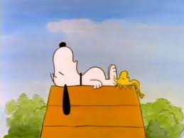 Snoopy sleeping on top of his dog house