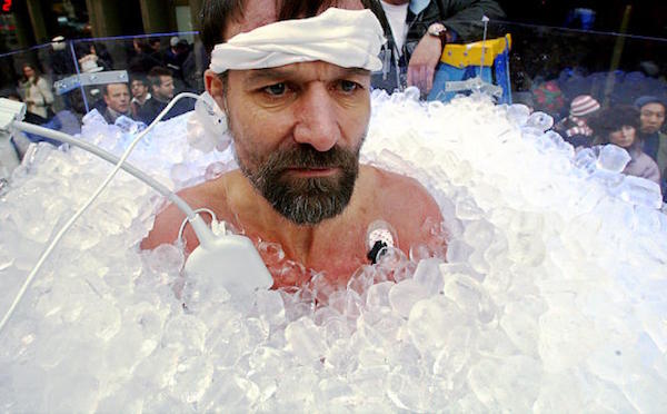 Wim Hof submerged in ice up to his neck and attached to electrodes for a scientific experiment surrounded by a crowd of people for Wim Hof Method Review