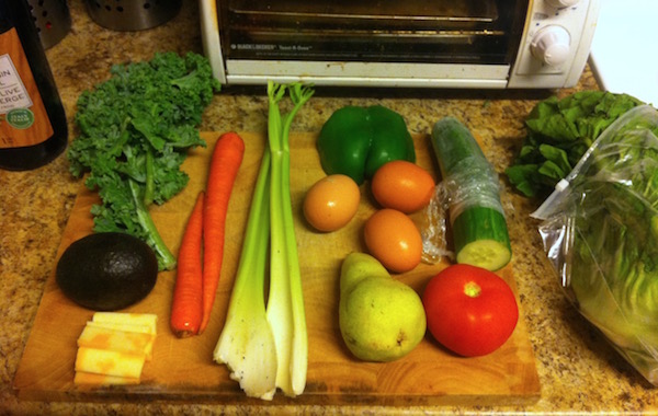 Salad ingredients kale, avocado, cheese, celery, boiled eggs, green pepper, cucumber, lettuce, pear