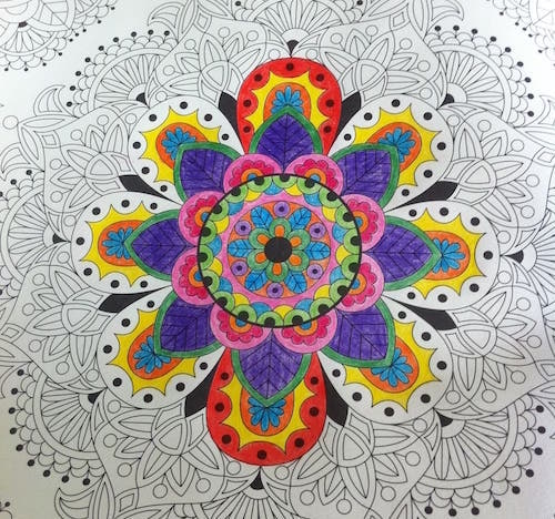 Partially coloured in image using pencil crayons in a colouring book with flower designs