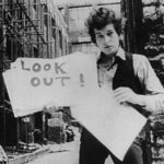 Bob Dylan holding a sign that says "Look Out!"