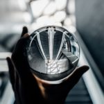 Hand holding clear glass globe showing upside down reflection of escalator