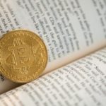 A coin representing a bitcoin in a book to show learning about crypto currency